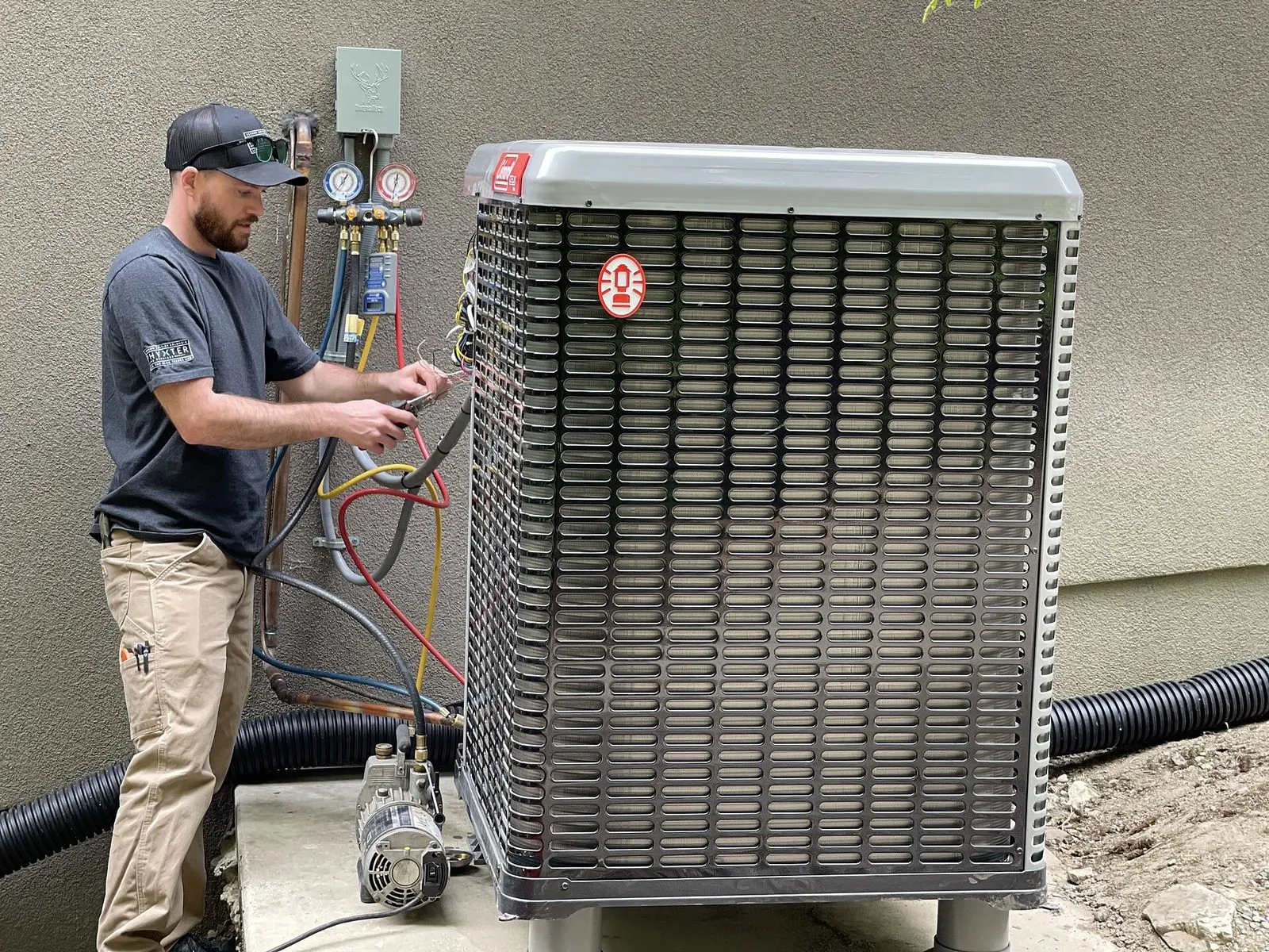 Installateur qui règle son manifold à côté d'une unité extérieure neuve